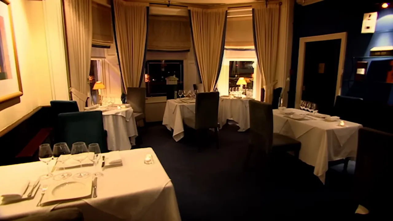 empty fine-dining restaurant dining room with tables set and soft lighting