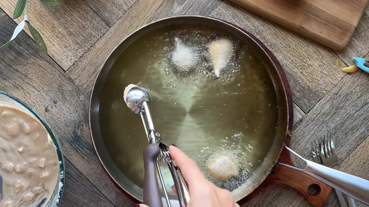 Scooping batter and dropping fritters into hot oil to fry