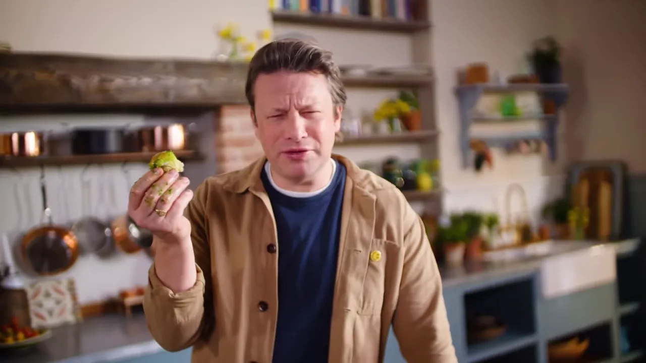 cook holding a bread roll with bright green wild garlic butter on their fingers in a home kitchen, showing the butter ready to be added to buns