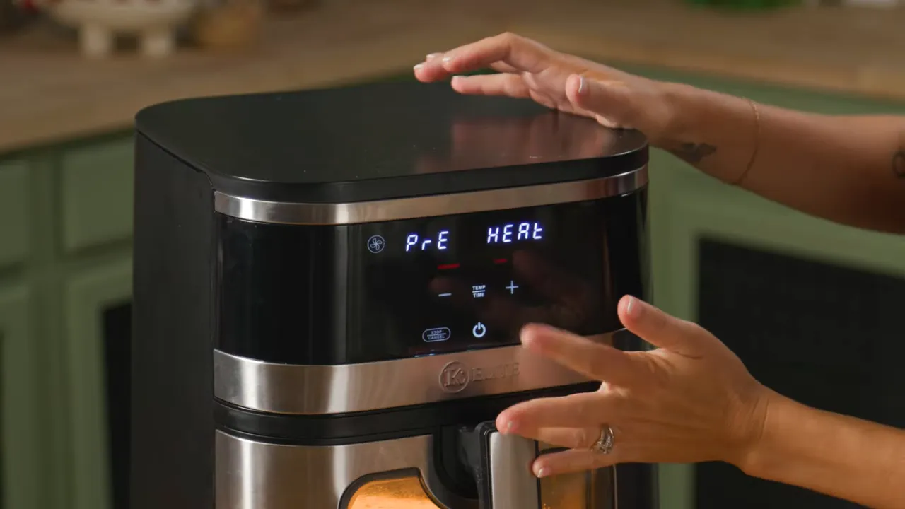 Close-up of air fryer control panel with hands adjusting settings and digital display.