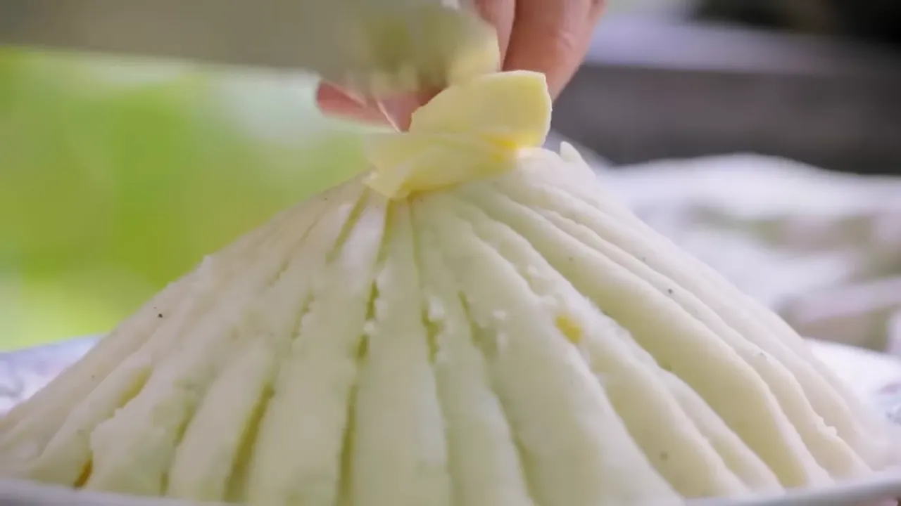 butter being placed on top of a ridged mound of mashed potato to create a 'volcano' presentation