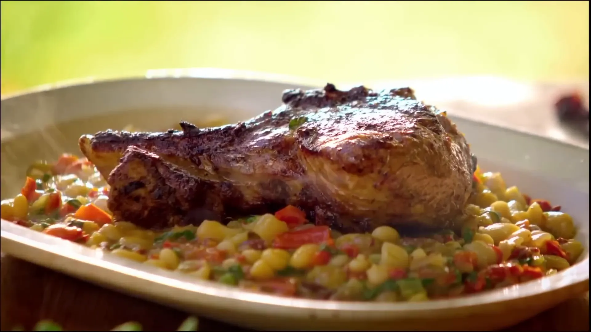 Plated creamy Spanish beans with a pork chop resting on top