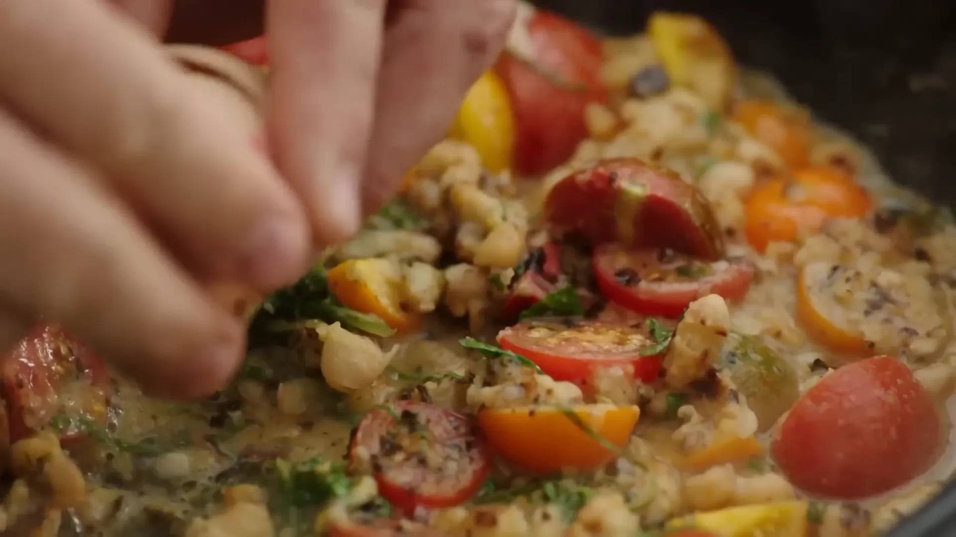 Cracking eggs into the pan of beans and tomatoes