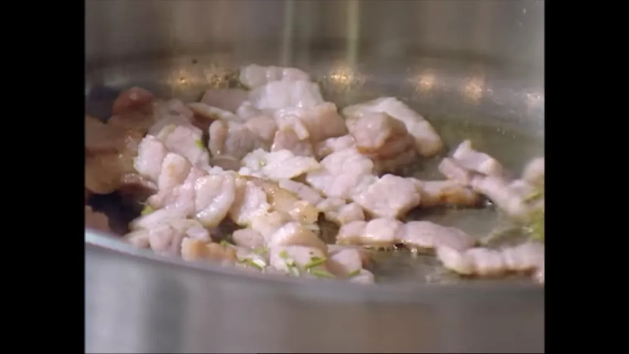 Finely chopped rosemary being added to frying bacon