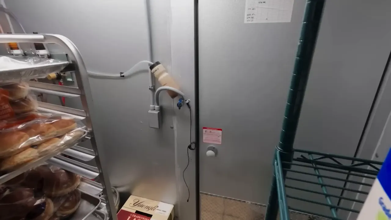 Walk‑in storage with racks of wrapped buns, labeled boxes and shelving showing visible mise en place.