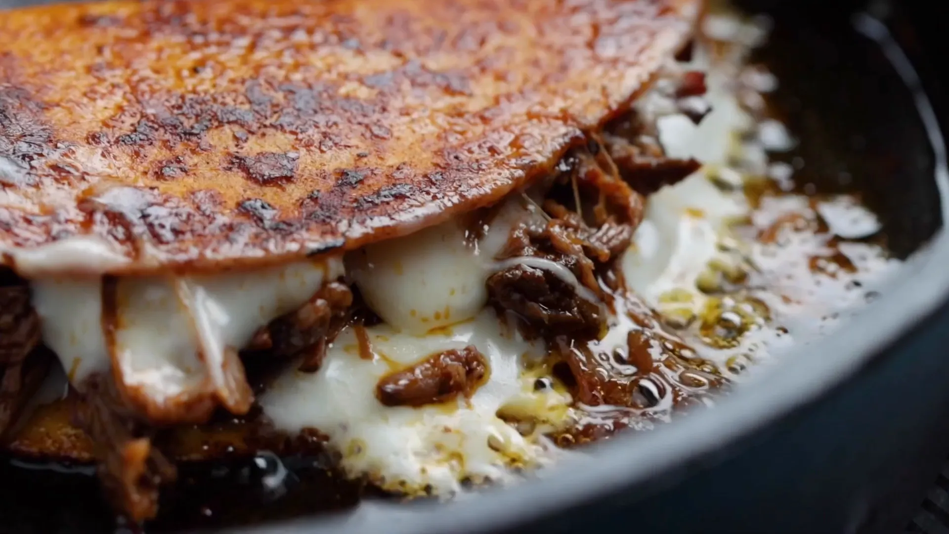 Golden birria tacos frying in a skillet