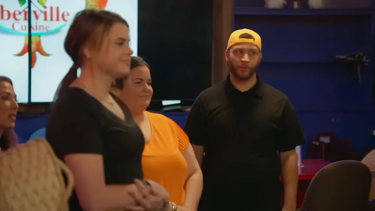 A small group of restaurant staff standing together in the dining area during a pre-service moment.