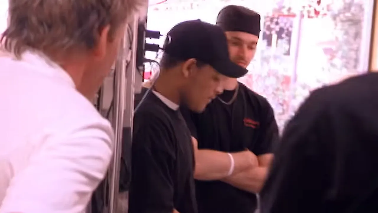 Pizzeria kitchen staff standing together near the pass in discussion