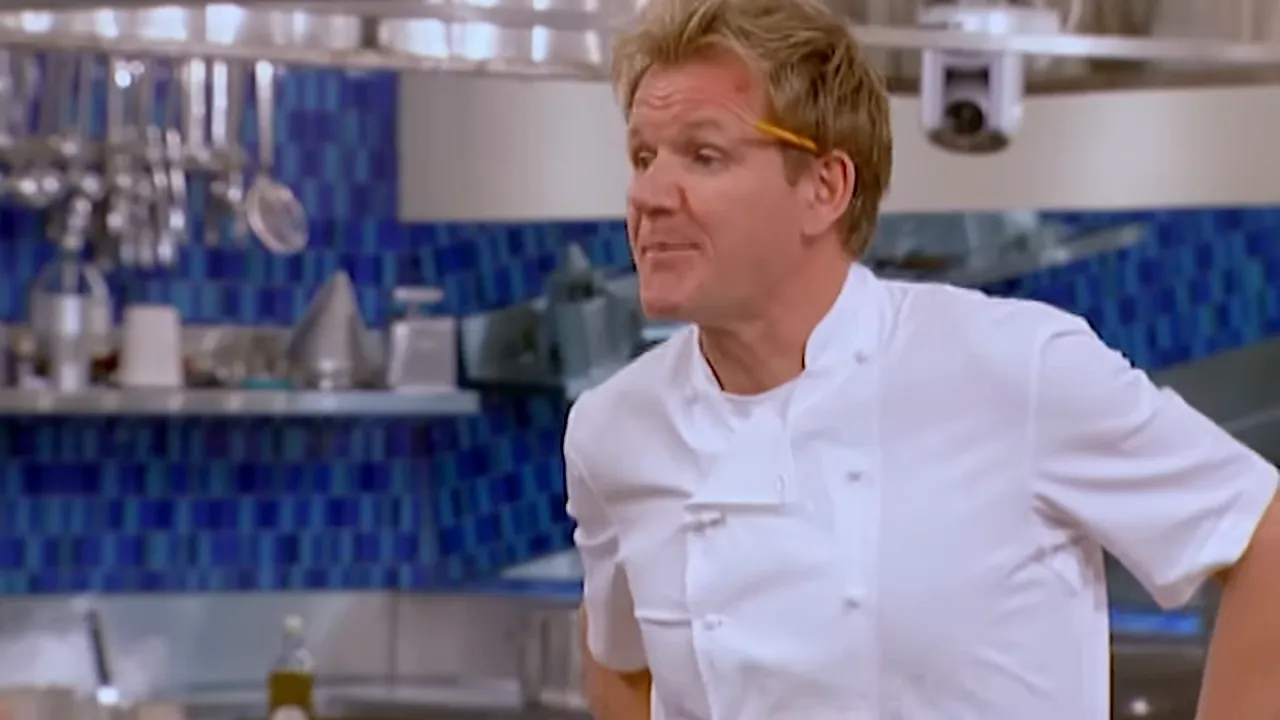 Head chef giving instructions to kitchen staff in a busy professional kitchen.