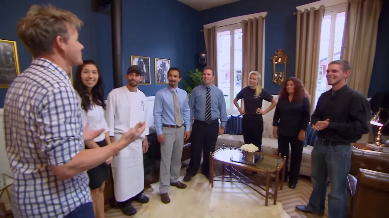 Hotel leader speaking to staff lined up in the renovated blue-accent lobby as the team listens.