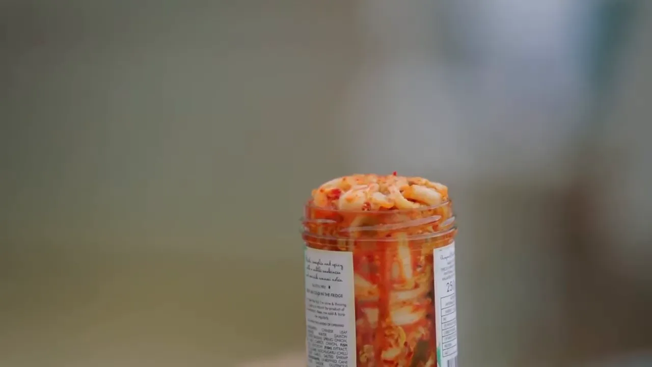Opening a jar of kimchi, vibrant red cabbage spilling out