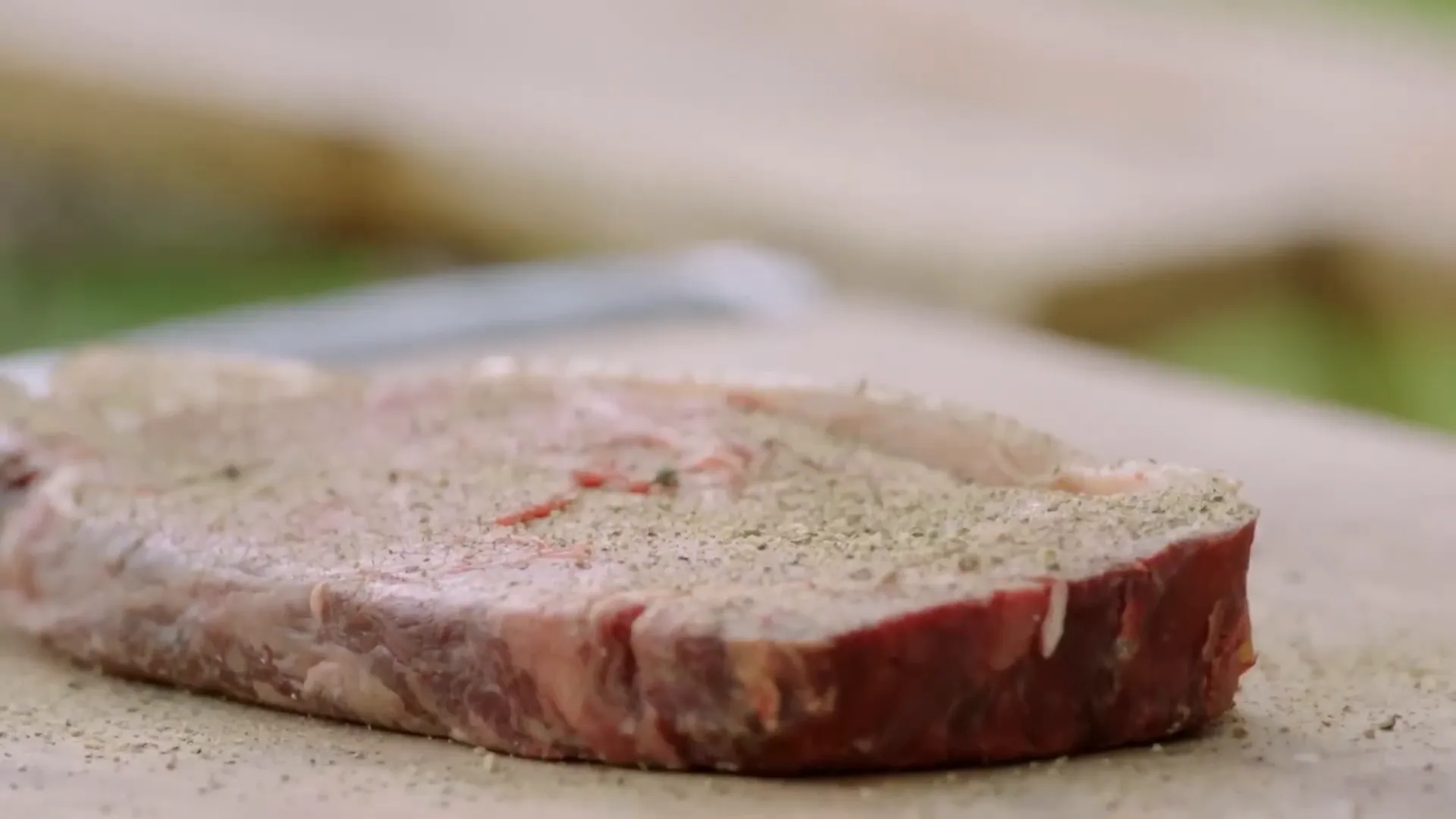 Seasoned sirloin steak cooking on the barbecue