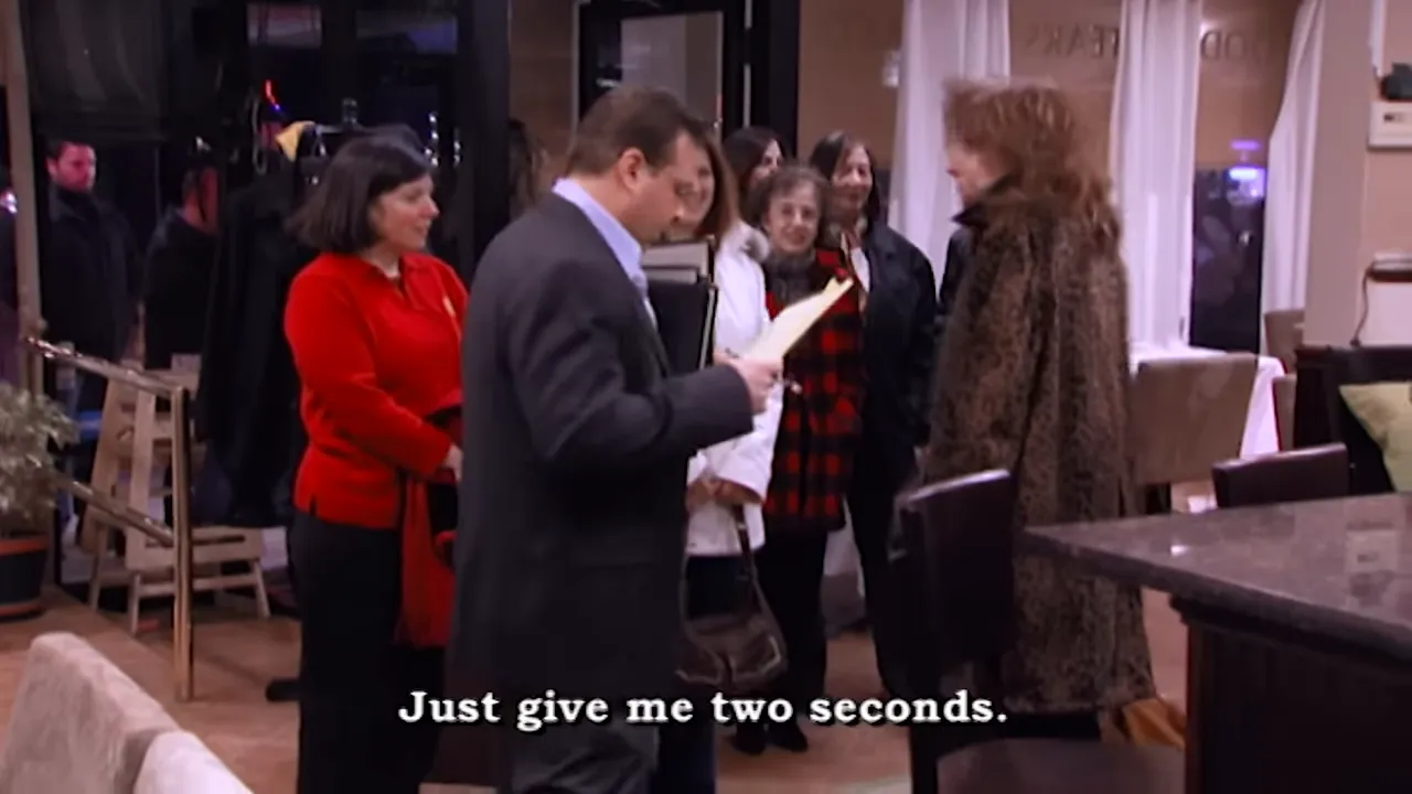 Host or manager checking a list while a group of guests wait near the entrance of a restaurant