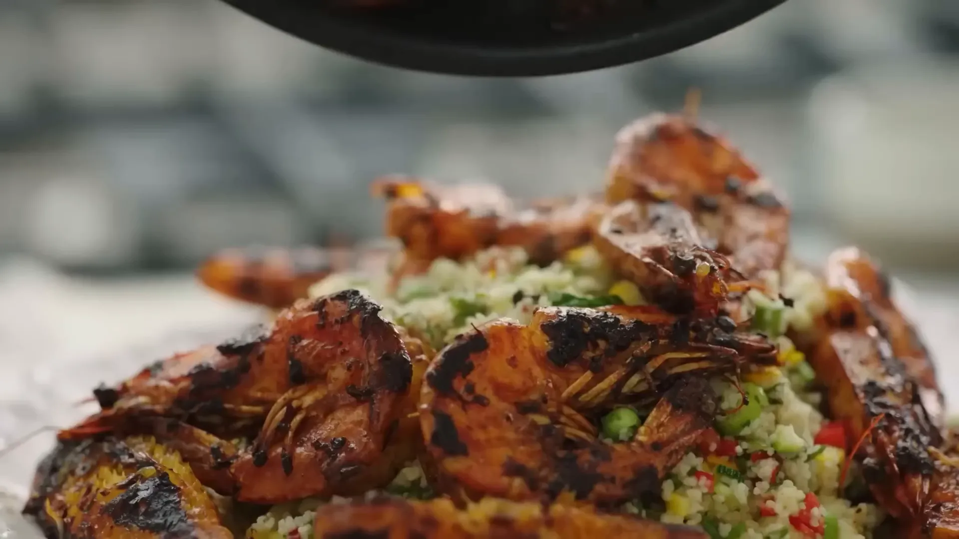 Saffron-marinated prawns cooking with orange slices over couscous