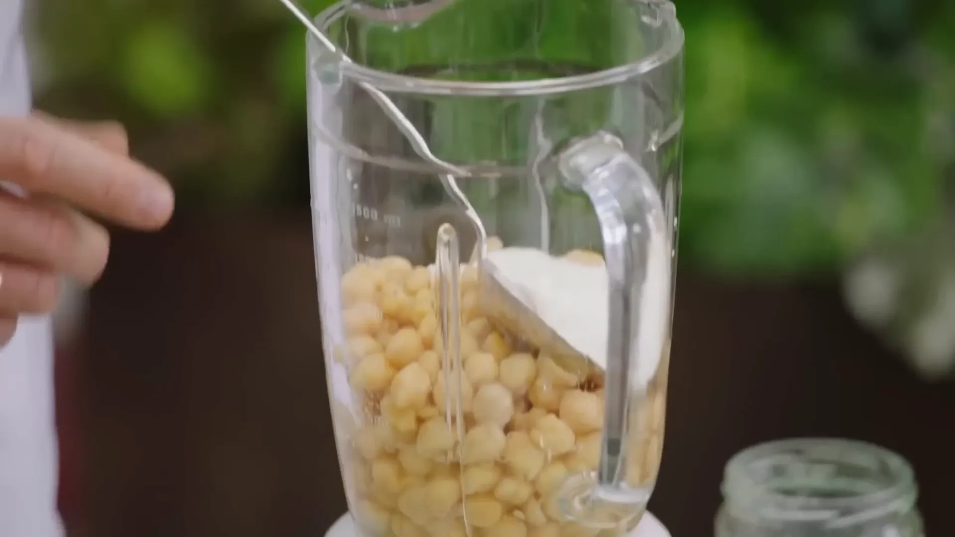 Blending chickpeas, yogurt, garlic, cayenne, lemon juice, and tahini for hummus