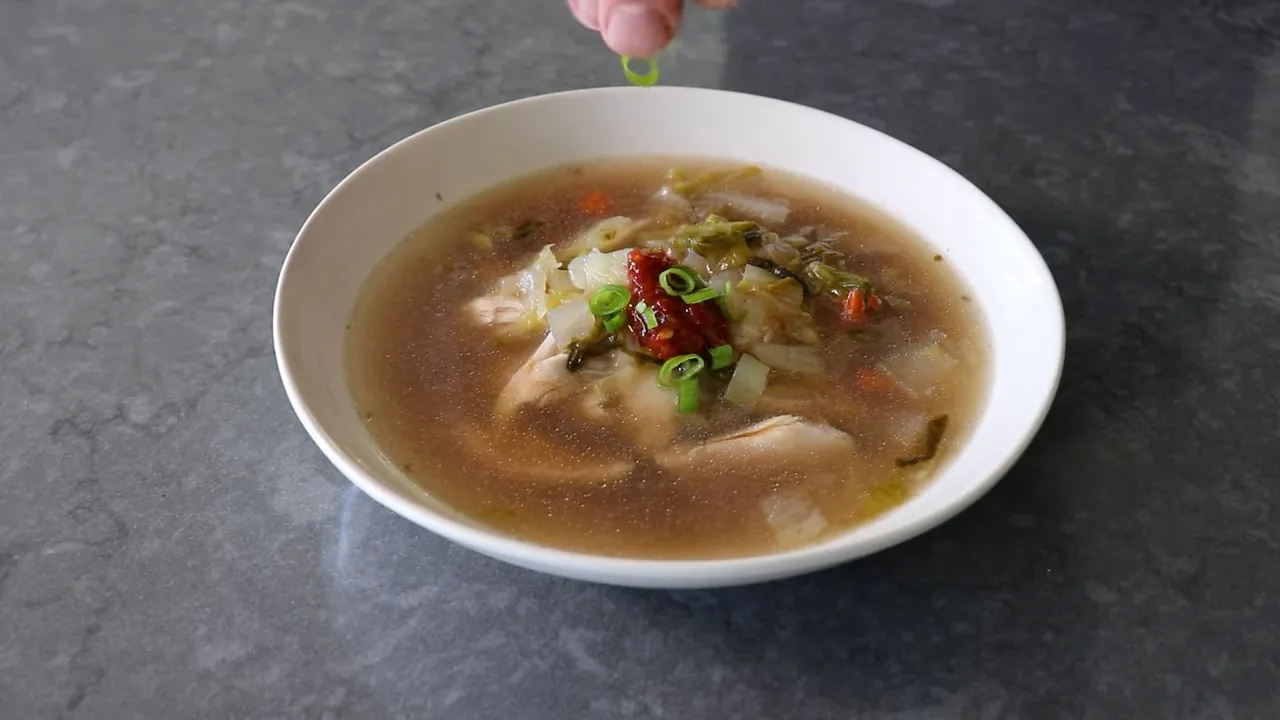 Bowl of no-water chicken soup topped with a dollop of sambal and freshly sliced green onions
