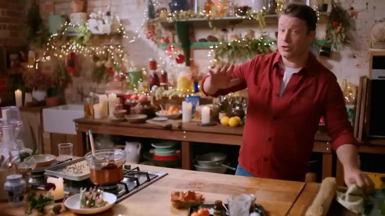 host gesturing in a warmly lit festive kitchen, workbench and ingredients in foreground