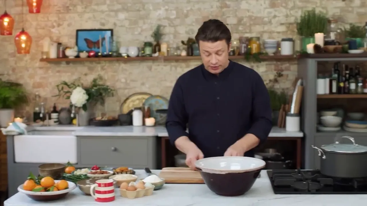 wide view of a kitchen counter with a large mixing bowl, ingredients and a presenter preparing to cook