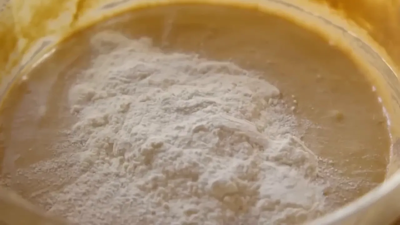 heap of flour sitting on top of chocolate batter in a glass bowl