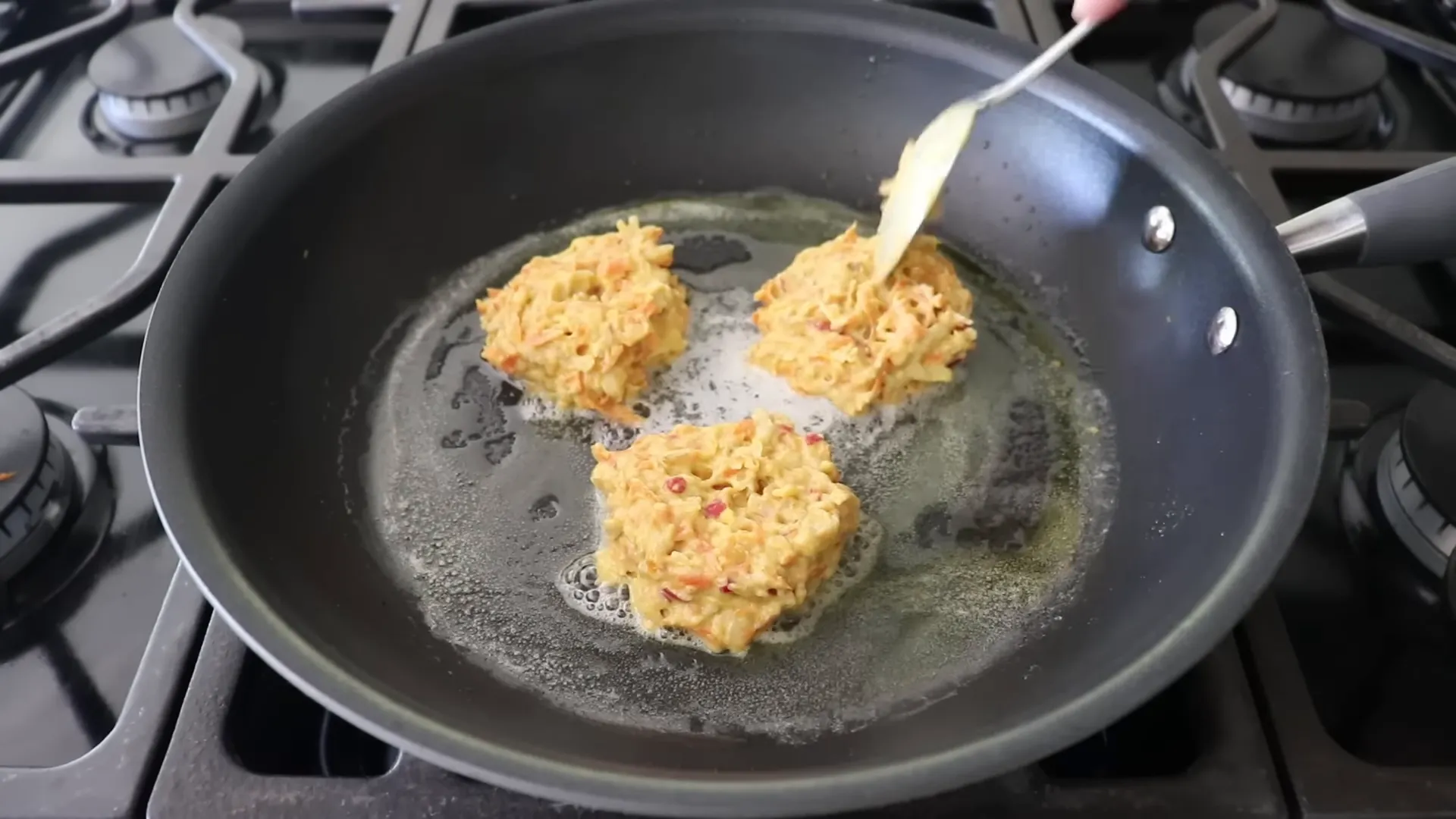 Spoon flattening pancakes in the skillet