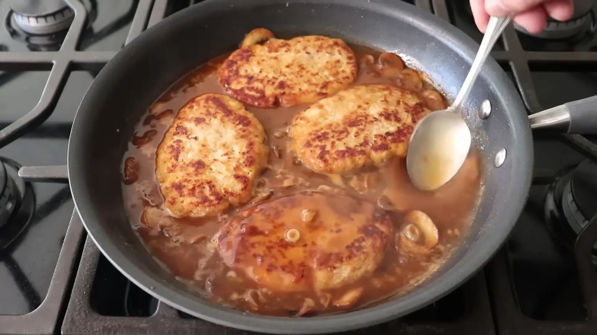 Chicken Salisbury steaks being basted in mushroom pan sauce