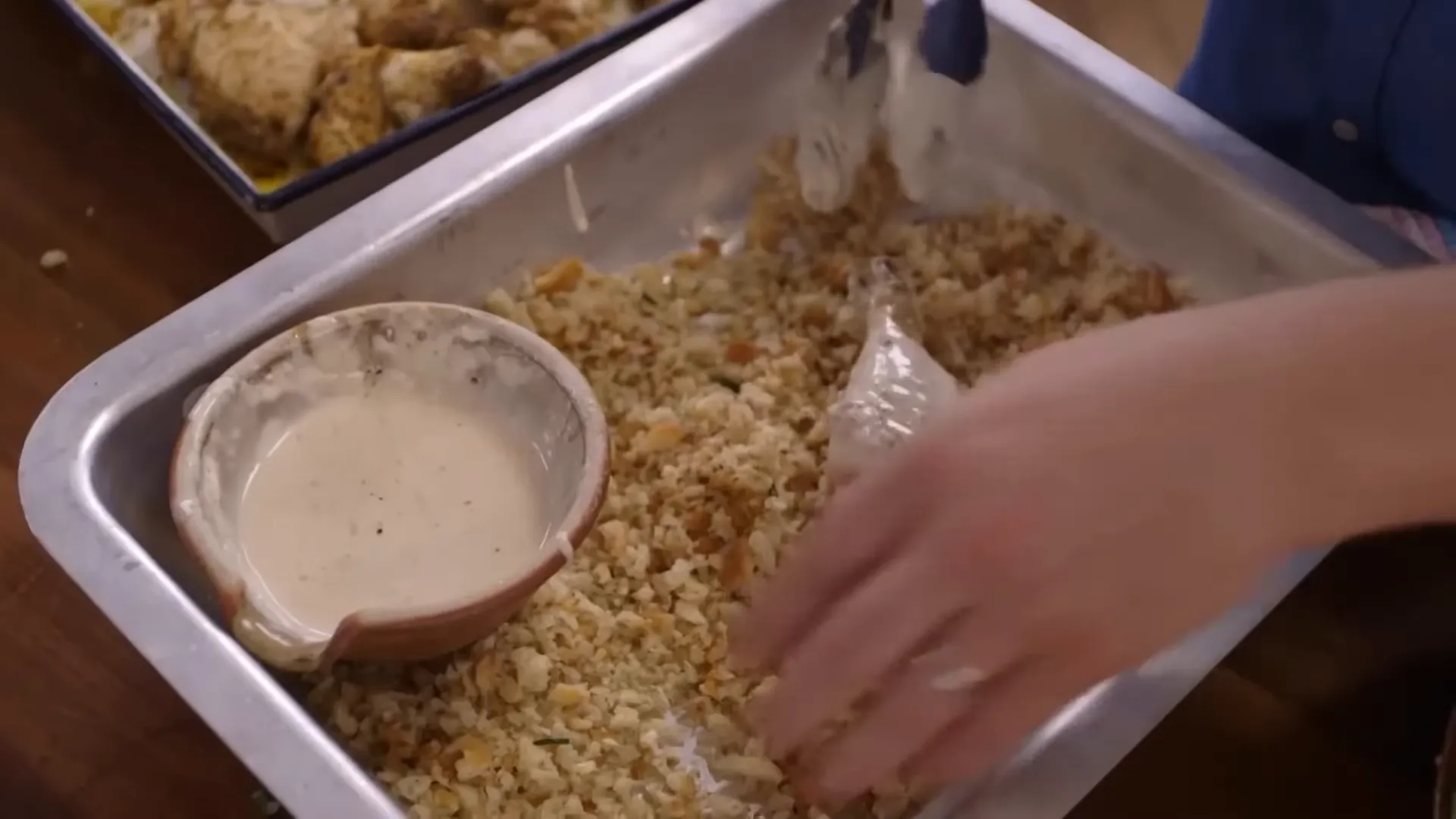 Dipping chicken into flour and water before breadcrumbs