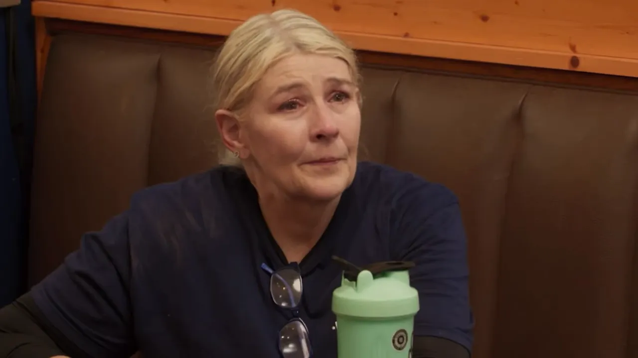 restaurant staff member visibly teary and upset, seated in a booth
