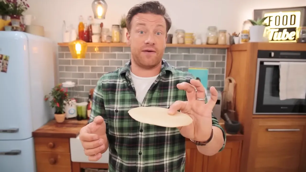 Single poppadom held between fingers in a home kitchen, ready to be topped