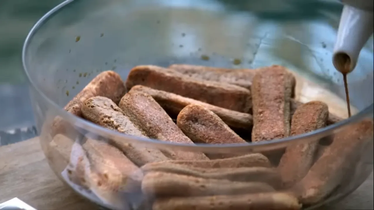 Pouring slightly sweetened coffee over sponge fingers
