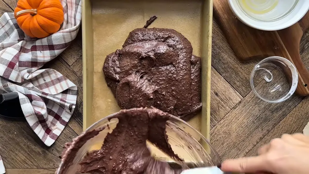 Pouring cake batter into a lined 9x13 inch pan