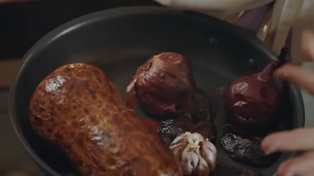 roasted butternut squash with caramelized onions and a bulb of garlic in a roasting pan