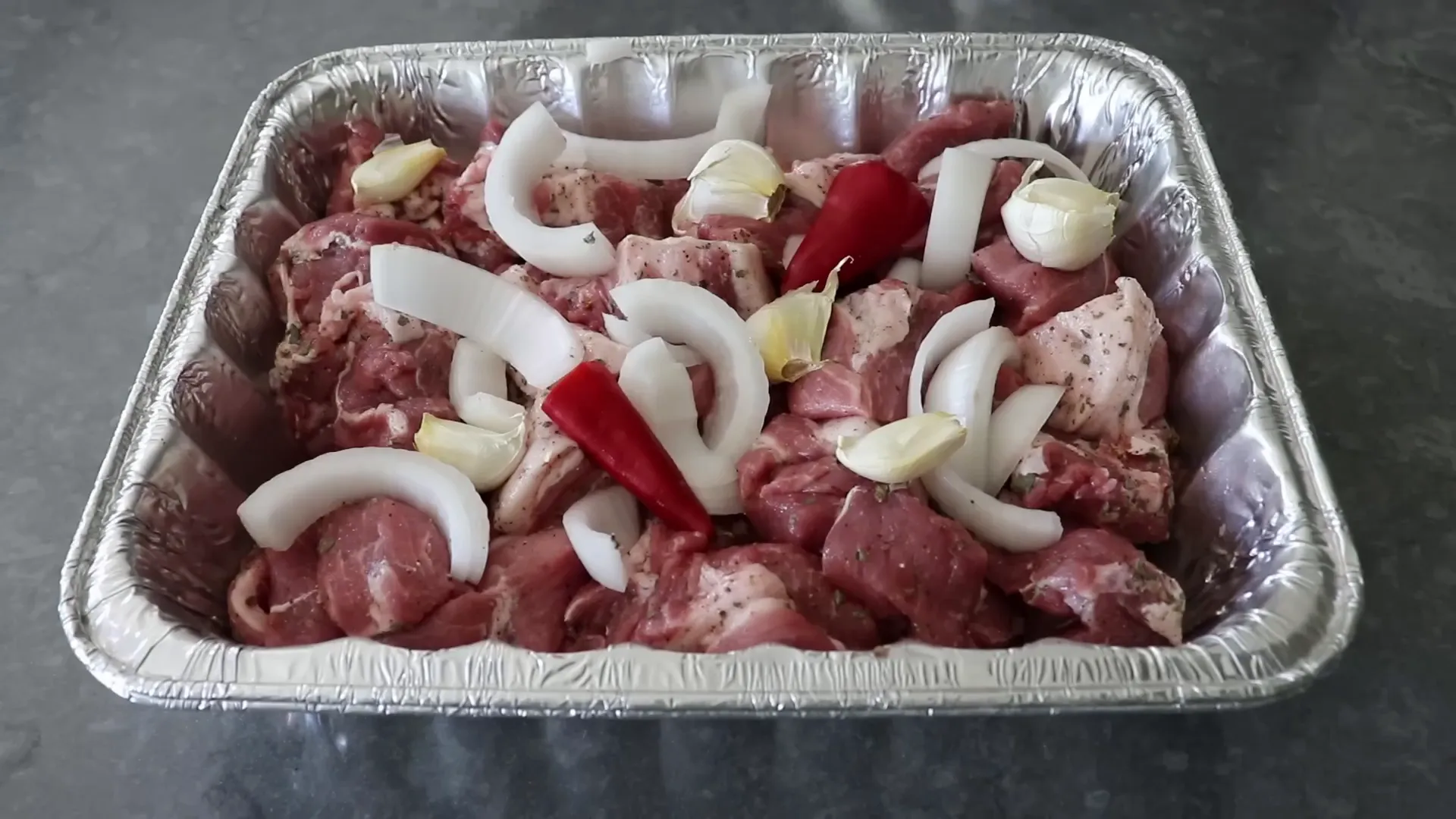 Seasoned pork topped with onions, chili, and garlic cloves