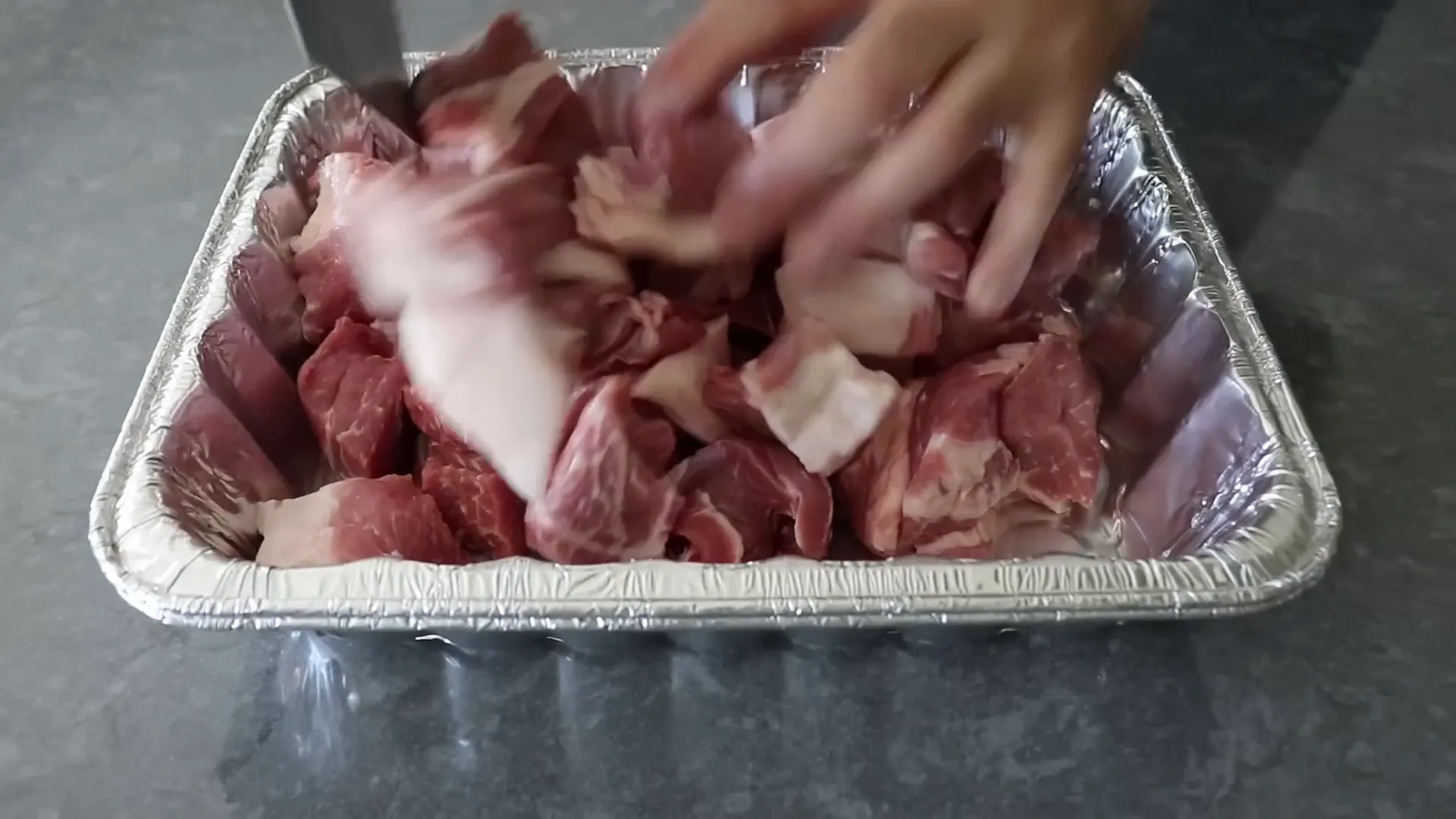 Chunks of pork in foil pans ready for seasoning