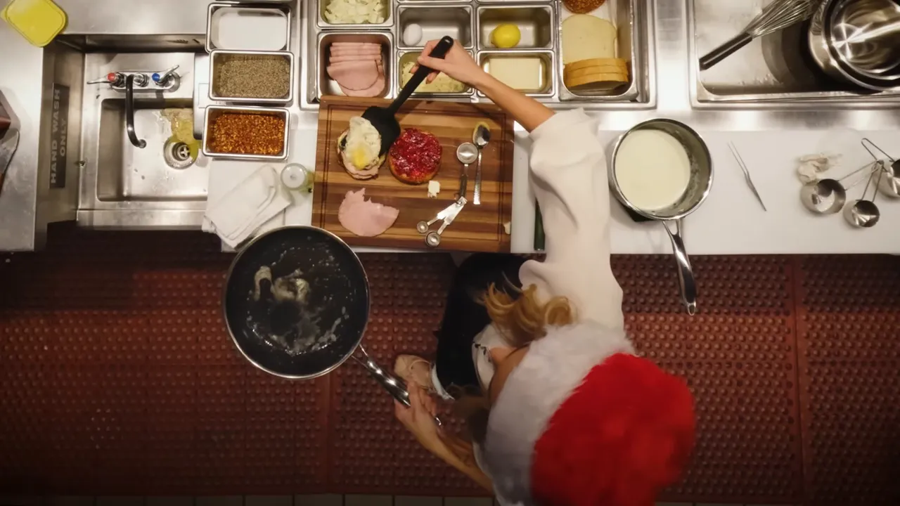 top-down view of sandwich assembly with béchamel pot, ham slice and cranberry-topped bun