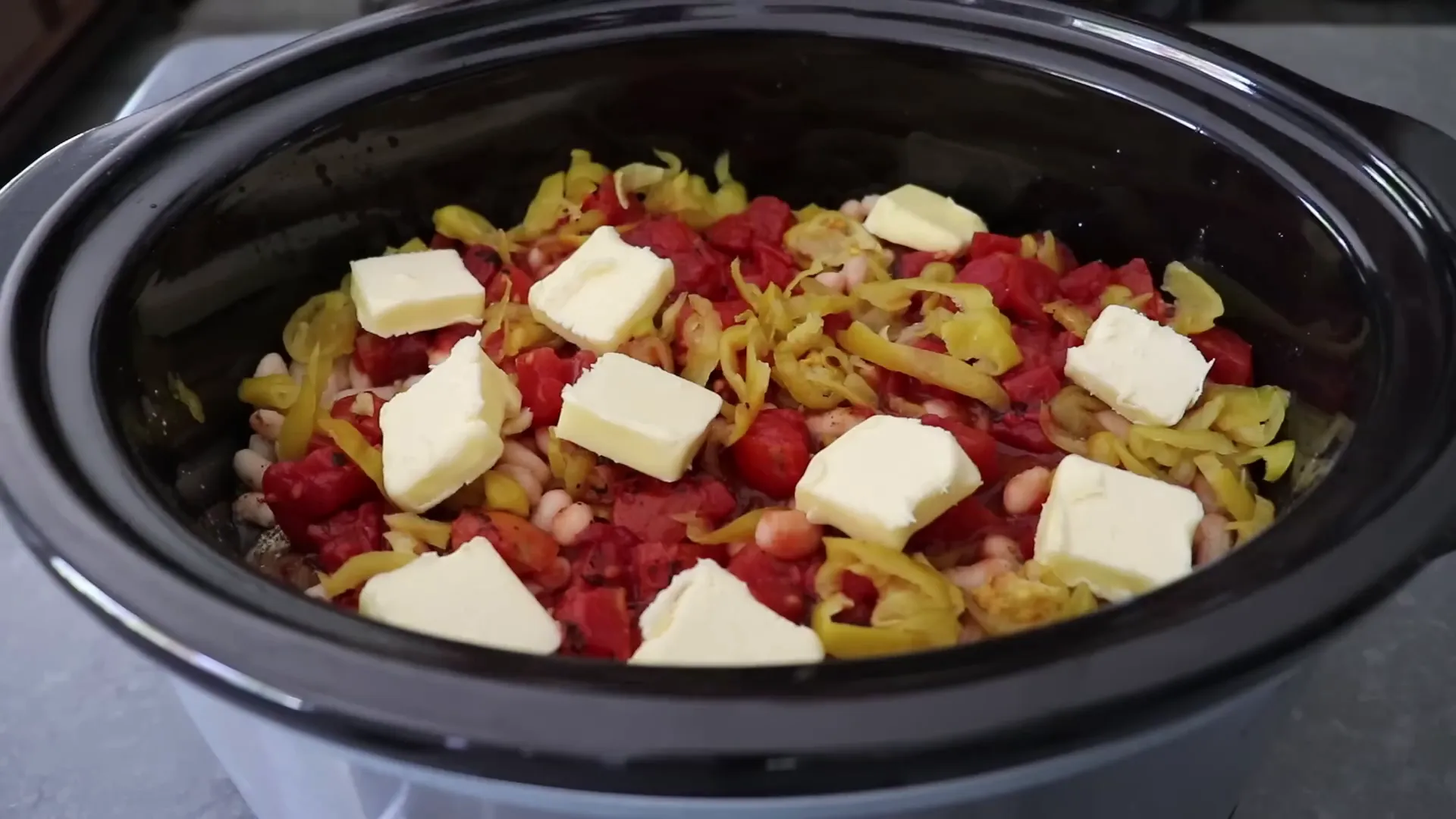 Stick of butter cut and placed over the assembled slow cooker ingredients