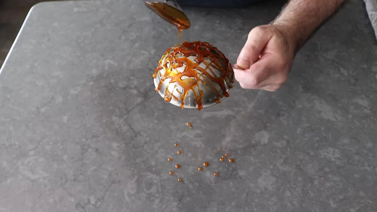 Completed caramel web covering the back of a metal bowl forming a sugar cage