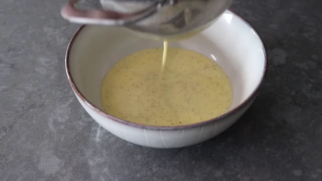 silky vanilla crème anglaise with visible vanilla specks being poured into a bowl
