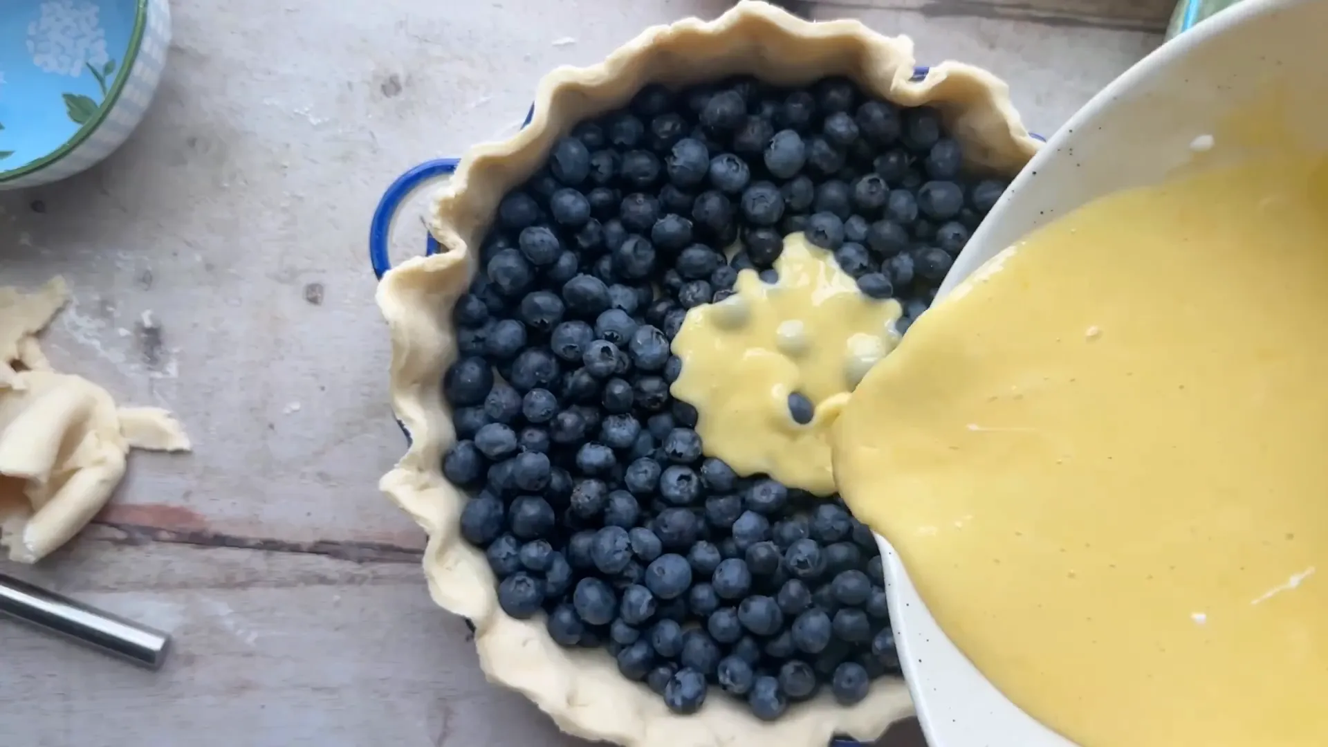Pie crust filled with fresh blueberries and custard poured on top