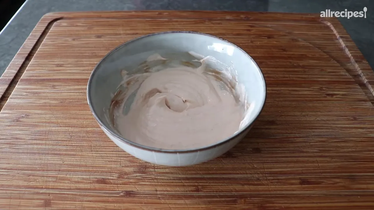 smooth light-pink dipping sauce in a ceramic bowl on a wooden cutting board