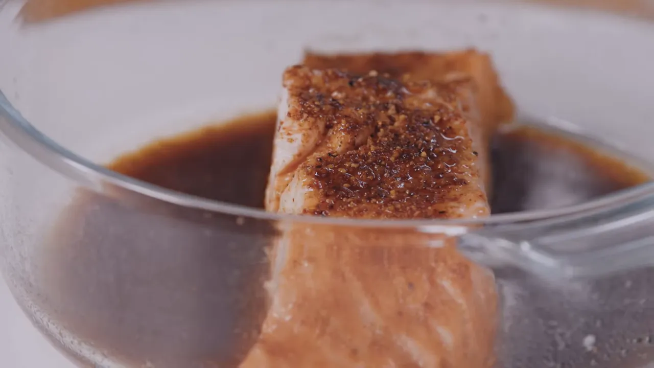 close-up of microwaved salmon fillet seasoned in a glass dish with sauce