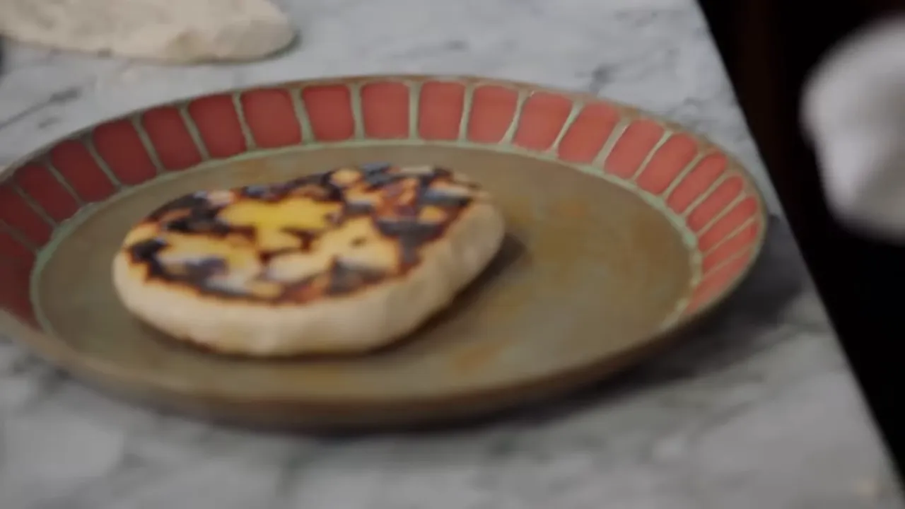 butter being rubbed onto cooked naan