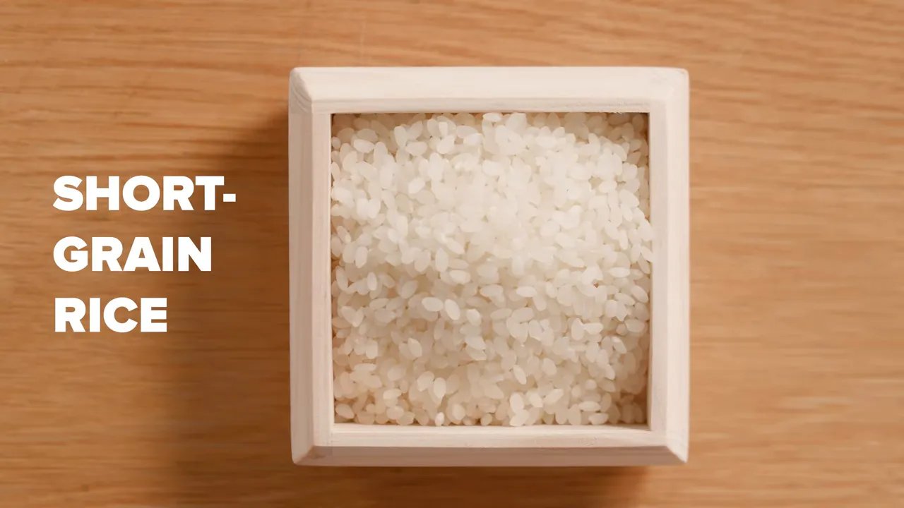 Top view of short‑grain rice tightly packed in a small wooden masu measuring box on a wooden table.