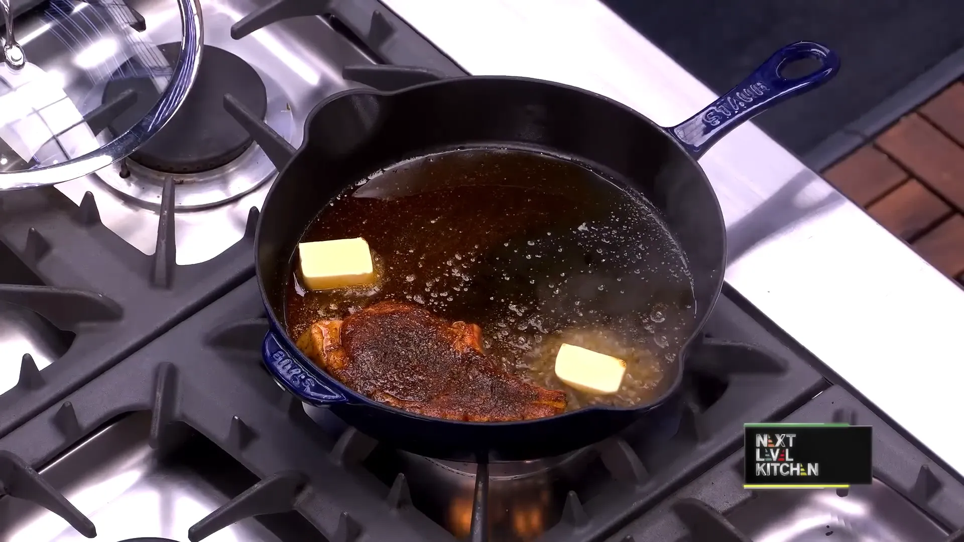 Pork chop sizzling in the pan with butter and thyme