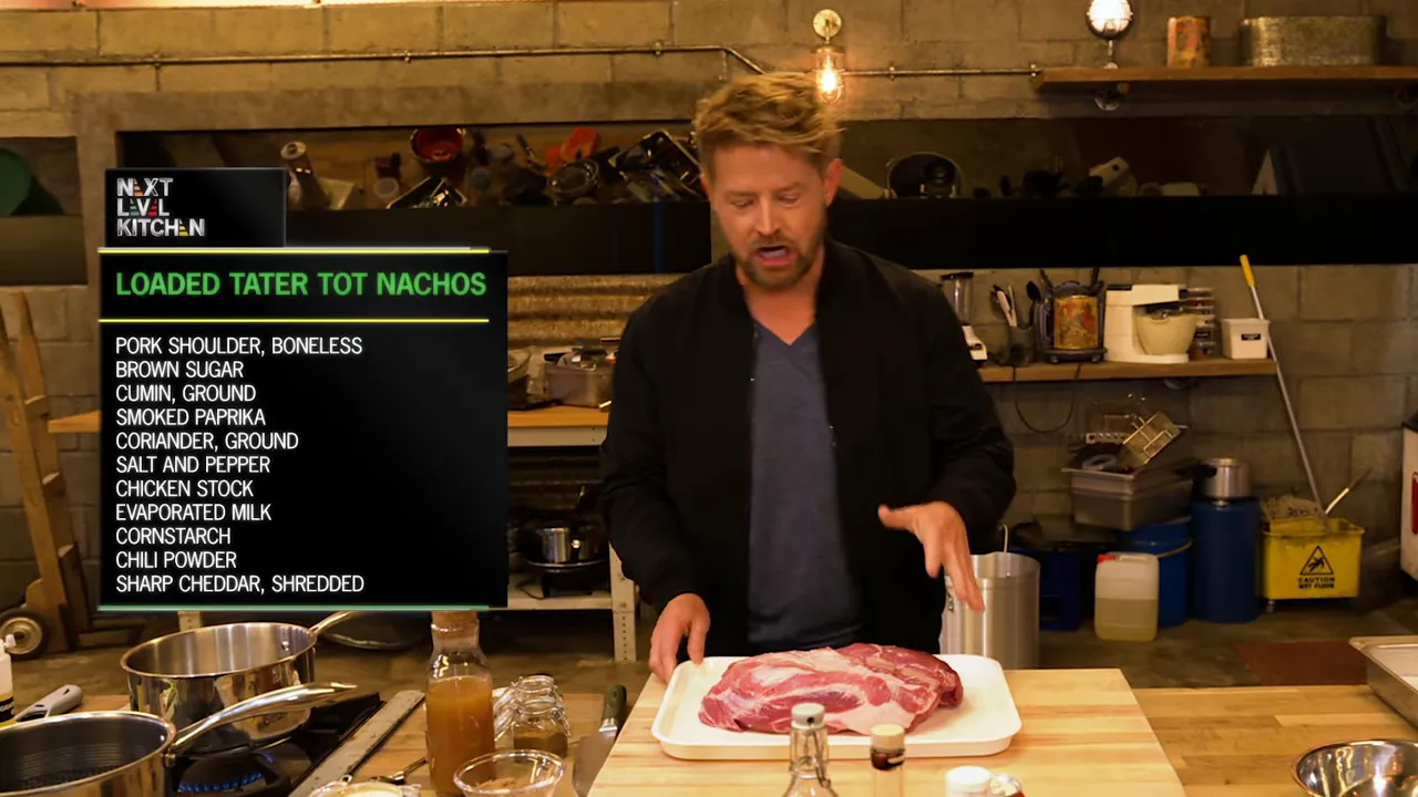 Wide shot of a cook at a prep counter with a raw pork shoulder on a tray and a clear ingredient list card reading 'Loaded Tater Tot Nachos'.