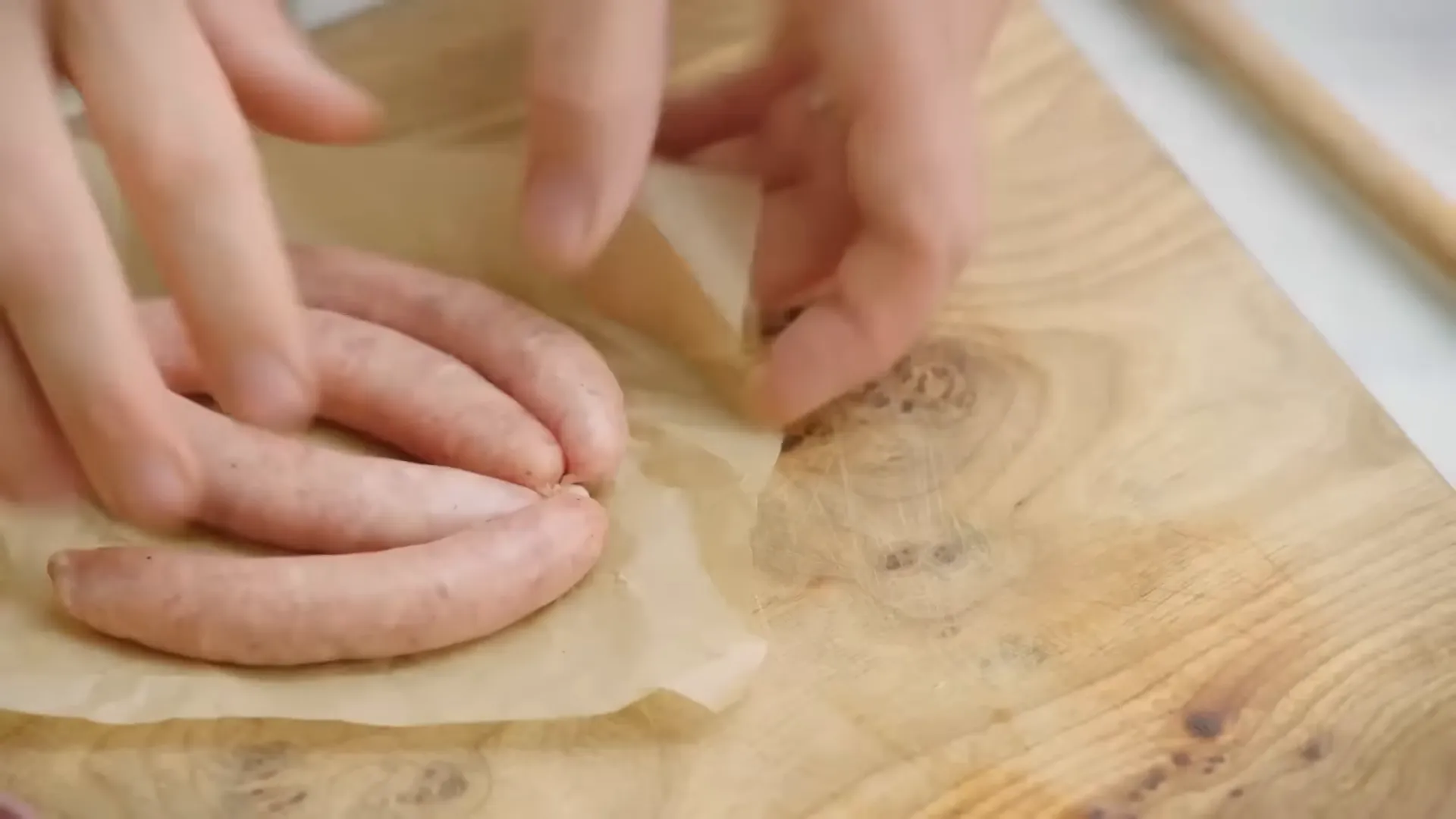 Four chipolata sausages ready to fry in a pan