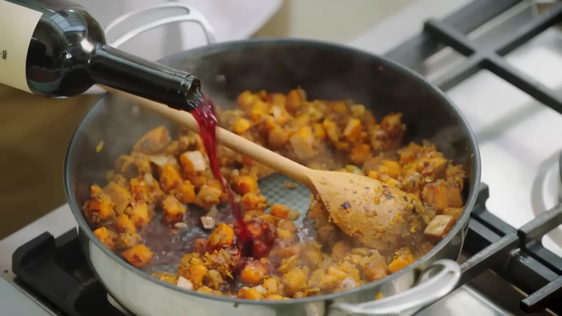 A splash of red wine being added to the pan