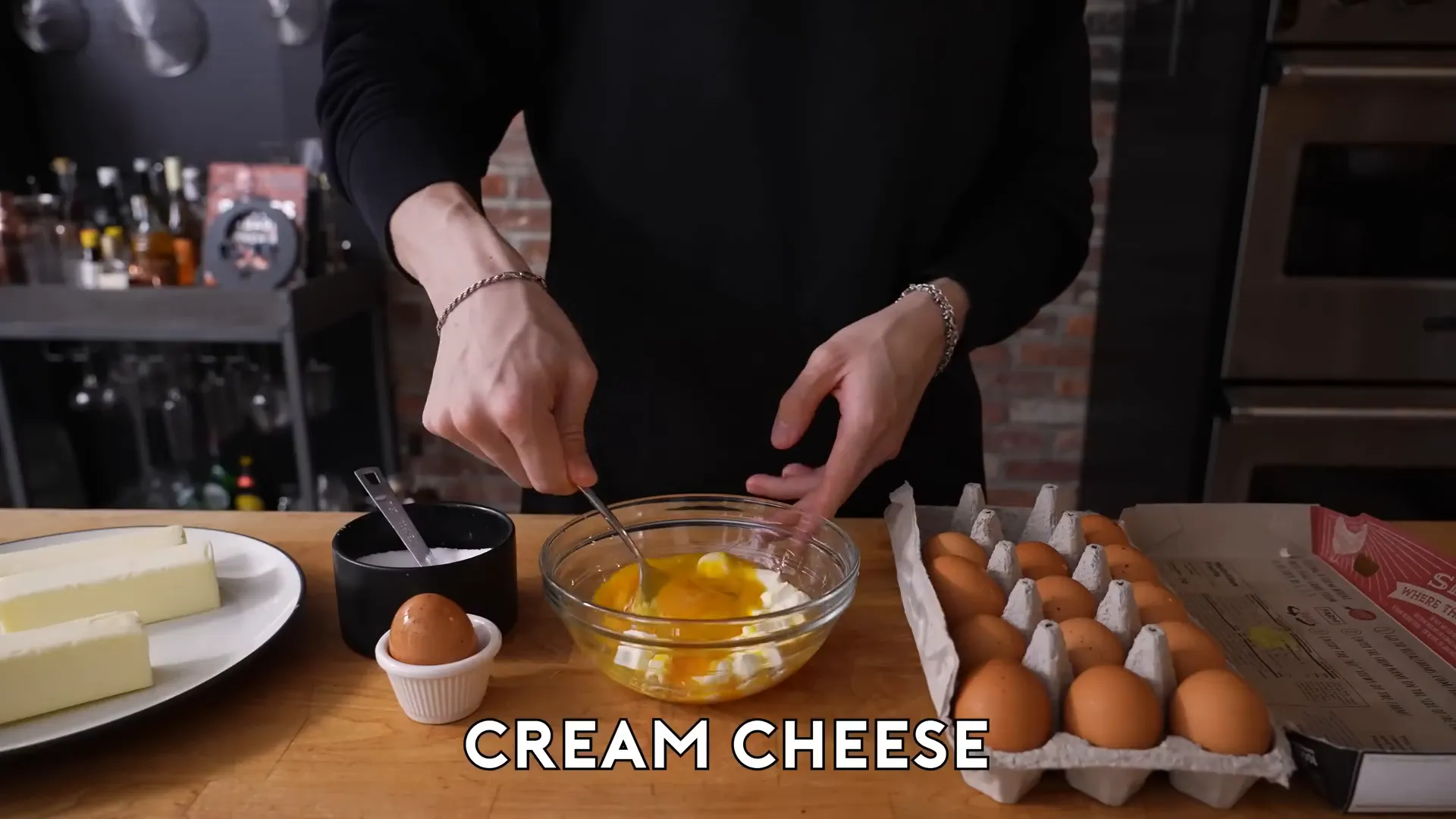 Cream cheese cubes being stirred into beaten eggs