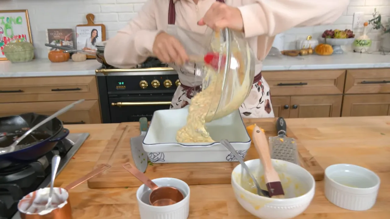 pouring cornbread casserole batter from a glass mixing bowl into a square ceramic baking dish