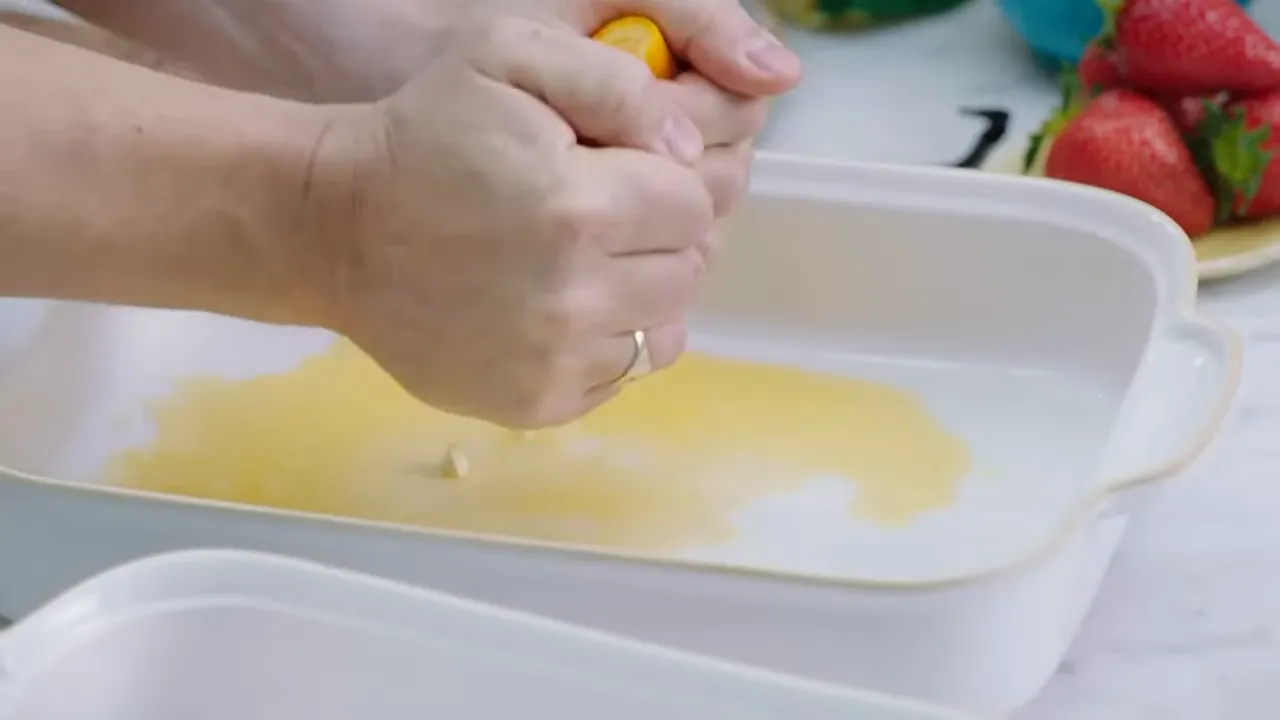 Squeezing oranges and scraping vanilla seeds into a bowl