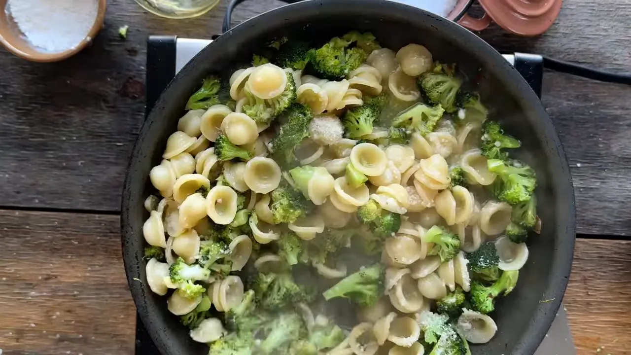Top-down view of finished orecchiette with broccoli and grated Parmesan in a skillet